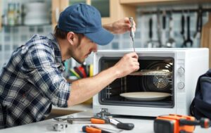 engineer-repairing-microwave-oven-kitchen-wearing-blue-cap-plaid-shirt_124865-71629